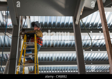 Caucasian construction worker standing on ladder Stock Photo