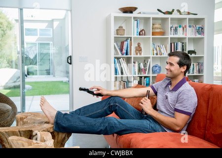 Mixed race man sitting on sofa watching television Stock Photo