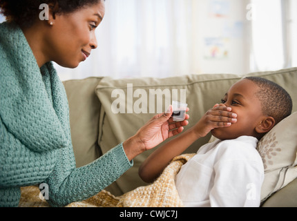 Black mother giving son cough syrup Stock Photo