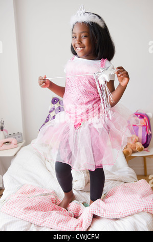 Black girl in fairy costume standing on bed Stock Photo