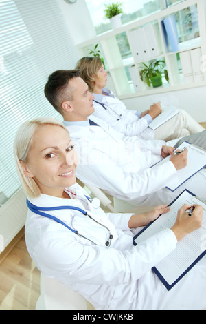 Portrait of three clinicians with clipboards making notes at medical conference Stock Photo