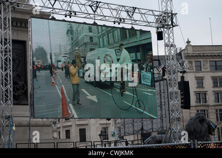 Man riding penny farthing bicycle on a large display screen in Trafalgar Square showing the New Years Day parade