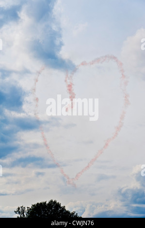 Pink smoke trails from an aerial aerobatics display team forming a love heart symbol in the sky. Concept image Stock Photo