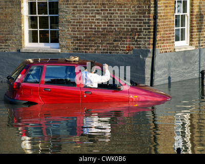 A motorist is climbs out of his car window as the high tide causes flooding along the River Thames - Richmond Stock Photo