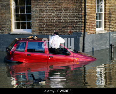 A motorist is climbs out of his car window as the high tide causes flooding along the River Thames - Richmond Stock Photo