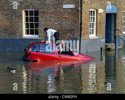 A motorist is climbs out of his car window as the high tide causes flooding along the River Thames - Richmond Stock Photo