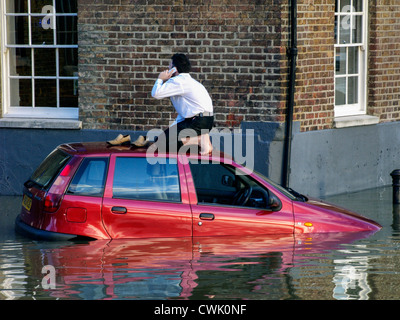 A stranded motorist phones for help from the top of his car  as the high tide causes flooding along the River Thames - Richmond Stock Photo