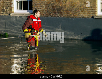 A fireman wades towards a stranded motorist as the high tide causes flooding along the River Thames - Richmond Stock Photo