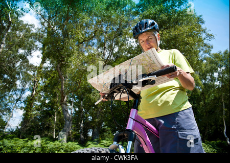 Adult female mountain biker checking route through a forest on a map Stock Photo
