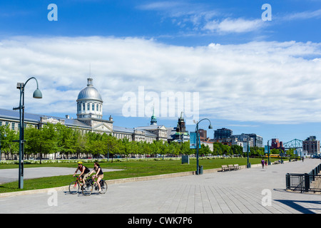 Cyclists on the riverfront promenade in the Quais du Vieux Port area with Bonsecours Market to left, Montreal, Quebec, Canada Stock Photo