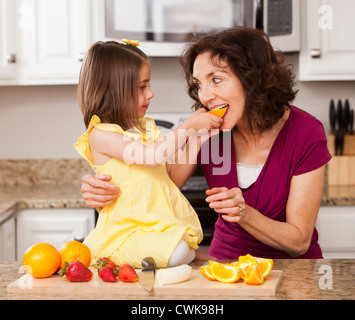 Caucasian grandmother and granddaughter eating fruit Stock Photo