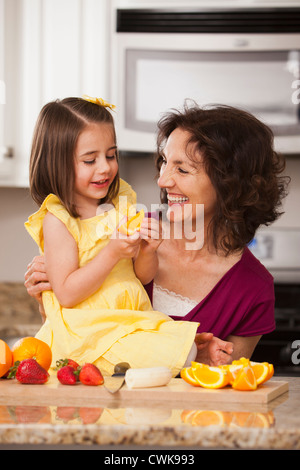 Caucasian grandmother and granddaughter eating fruit Stock Photo