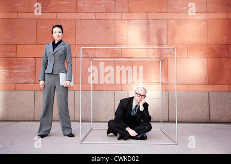 Businesswoman standing next to co-worker in box Stock Photo
