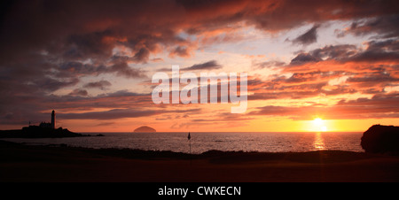 Turnberry lighthouse and Ailsa Craig at sunset - golf flag in foreground 10th Green. Stock Photo