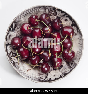 some cherries on an antique plate