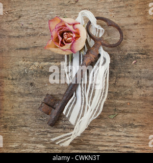 old rusty key with flower on a wooden background Stock Photo