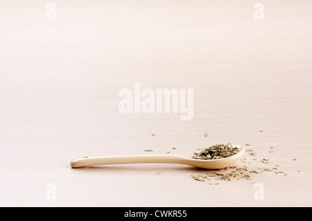 Tarragon in a spoon with some spilt over the wooden background Stock Photo