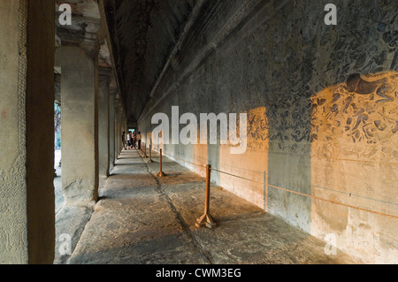 Horizontal view of a guide and a group of tourists standing infront the amazing carvings at Prasat Angkor Wat, Cambodia Stock Photo