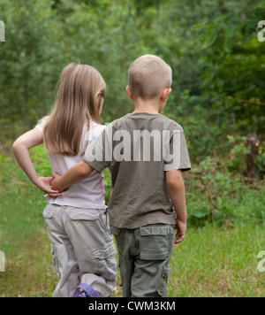 Two children walk arm in arm in a wood Stock Photo: 21925919 - Alamy