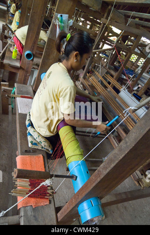 Vertical close up of women weaving the silk threads into fabric on a loom at a silk producing factory in Cambodia. Stock Photo