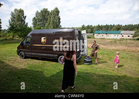 UPS delivery man unloading package for business in the home entrepreneurial mom. Zawady Central Poland Stock Photo