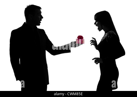 one caucasian couple man kneeling offering present gift and woman surprised in studio silhouette isolated on white background Stock Photo