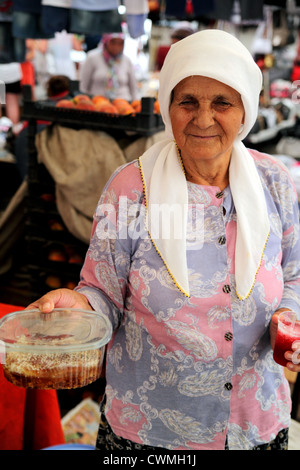 Upright view of elderly Turkish woman wearing headscarf holding honeycomb for sale in market near Dalyan Turkey Stock Photo