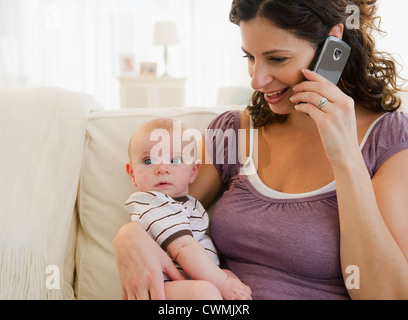 USA, New Jersey, Jersey City, Mother with baby boy (2-5 months) using mobile phone Stock Photo