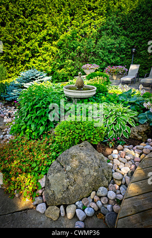 Lush perennial garden with fountain plants and trees Stock Photo