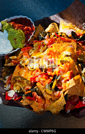 Basket of nachos with cheese jalapeno and toppings Stock Photo