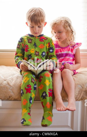 USA, Utah, Salt Lake, Brother (6-7) and sister (4-5) reading book together Stock Photo