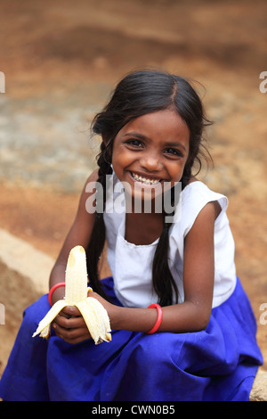 Young Indian rural girl eating a banana Andhra Pradesh South India Stock Photo