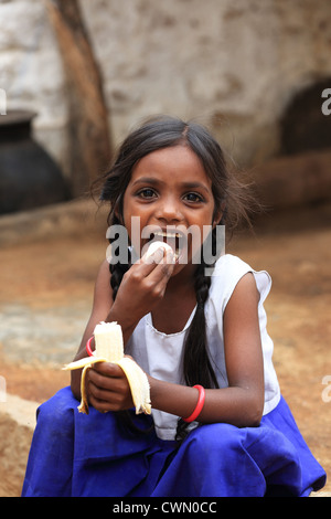 Young Indian rural girl eating a banana Andhra Pradesh South India Stock Photo