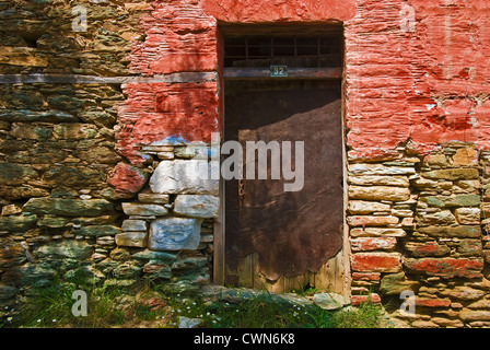 Colorful facade of an old stone cottage with weathered metal door and house number on Pelion Peninsular, Thessaly, Greece Stock Photo