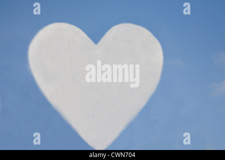 White cloud in the shape of a heart silhouetted against a blue sky Stock Photo