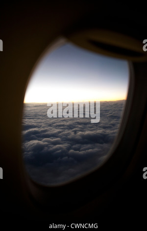 View of the low sun in cloudy skies from an airplane window during flight. Stock Photo