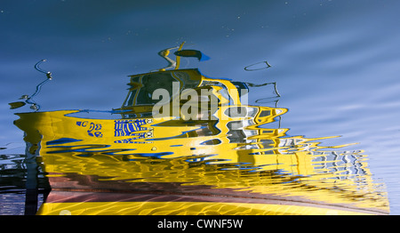 Yellow boat reflected on the water. Stock Photo