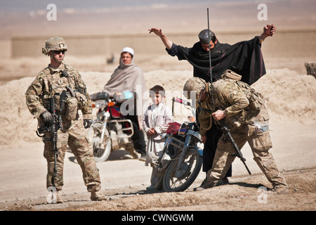 A U.S. Army soldier searches travelers at a traffic checkpoint outside Combat Outpost Yosef Khel, March 9, 2012 in Paktika Province, Afghanistan. The US Army soldiers were conducting traffic checkpoints and clearing missions all day with a platoon from the Afghan National Army. Stock Photo