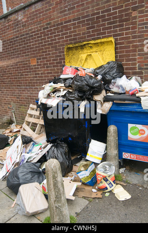 overflowing bin bins full dumpster dumpster in back alley alleyway trash rubbish can cans collection service Stock Photo