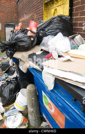 overflowing bin bins full dumpster dumpster in back alley alleyway trash rubbish can cans collection service Stock Photo