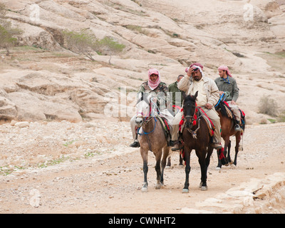 Petra historical and archaeological site in Jordan is a vast area and you can hire transport like these horses, here with owners Stock Photo