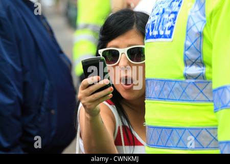 Female EDL supporter uses a mobile phone to film UAF counter demonstrators during a rally in Walthamstow
