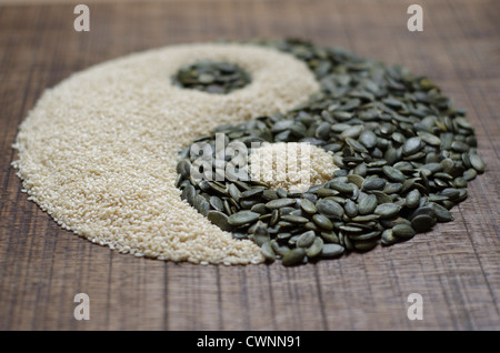 The yin yang created out of pumpkin seeds and sesame seeds on a dark wood surface Stock Photo