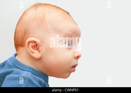Side View of Sweet Curious Baby on Light Background Stock Photo