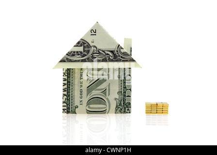 House folded from a dollar bill beside miniature gold bars, isolated on 100% white background Stock Photo