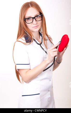 Portrait of a young beautiful female doctor checking red heart. Stock Photo