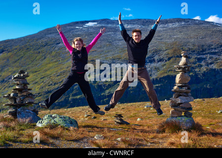 Young happy couple jumping on mountain background. Stock Photo