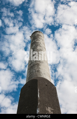 Old factory chimney no longer polluting the air against a blue summer sky Stock Photo