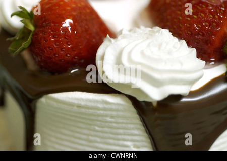 Cake topped with strawberries, chocolate and white cream Stock Photo
