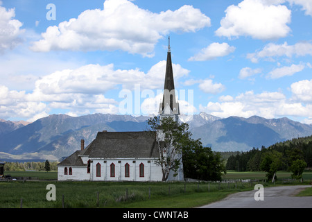 Eugene Mission Church, near Cranbrook, Canada. Sits in the midst of green pastures with mountains rising in the background. Stock Photo